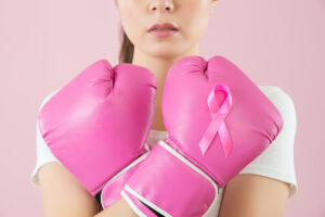 Buste de femme, les bras croisés devant elle, avec 2 gros gants de boxe rose et un ruban de même couleur